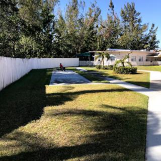 A serene outdoor space featuring a well-maintained yard surrounded by trees and a white fence.