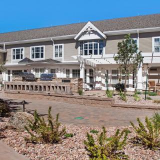 A large residential building with a landscaped garden in the foreground.