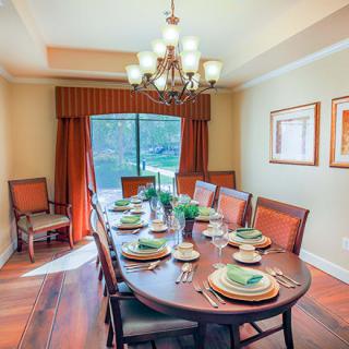 A well-decorated dining room with a large table set for a meal and a chandelier overhead.