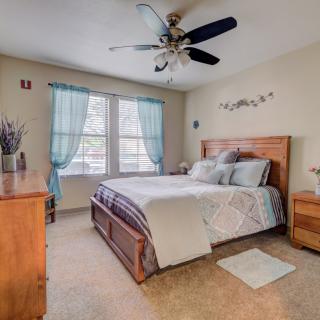 A cozy bedroom with a wooden bed frame, blue curtains, and a ceiling fan.