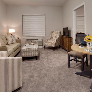 A cozy living room with a sofa, armchair, coffee table, and television.