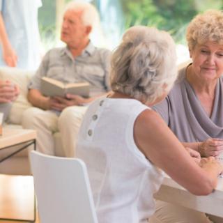 A group of seniors socializing and conversing indoors.
