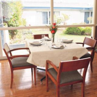 A dining table set for four, with natural light streaming through large windows.