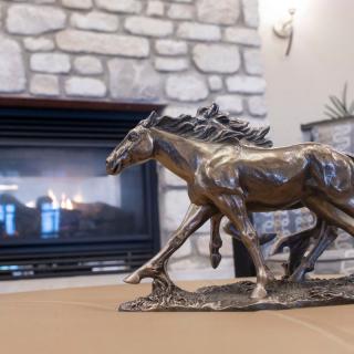 A bronze horse sculpture placed in front of a stone fireplace.