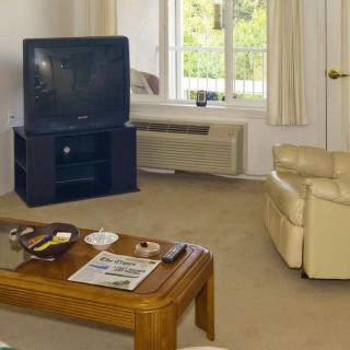 A cozy living room with a television, beige armchair, and a wooden coffee table.