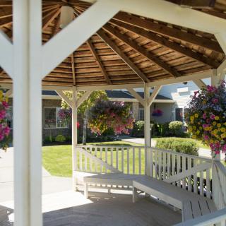 A peaceful gazebo surrounded by a well-kept garden with hanging flower baskets.