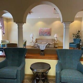 A cozy lounge area featuring armchairs and a sofa, separated by elegant archways.