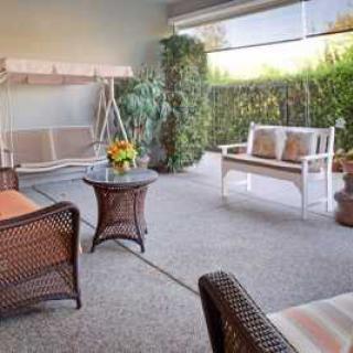 A cozy outdoor patio with a swing and comfortable seating surrounded by greenery.