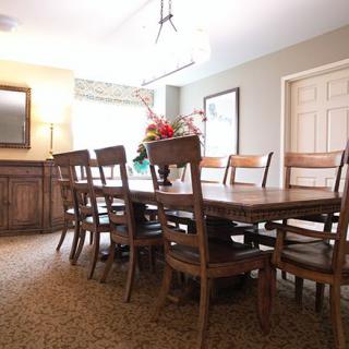 A well-furnished dining room with a large wooden table and chairs, enhanced by stylish lighting and decor.