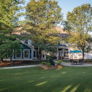 A beautiful house with a spacious lawn and patio surrounded by trees.