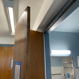 A partially opened wooden door in a well-lit interior space.