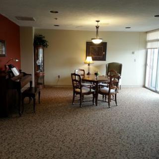 A spacious dining area featuring a table and chairs, complemented by warm lighting and soft carpeting.