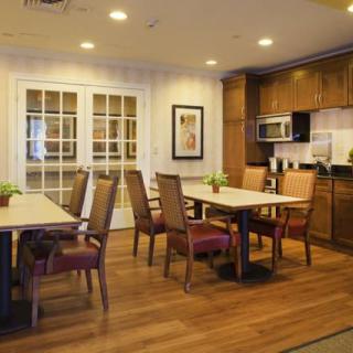 A modern dining and kitchen area featuring wooden floors, tables, chairs, and well-lit interior.