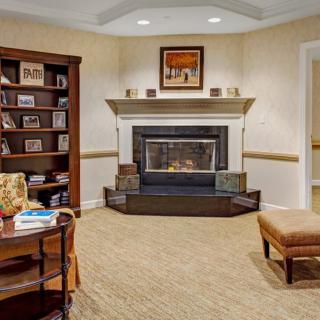 A cozy living room with a fireplace and bookshelf, featuring comfortable seating and warm interior design.