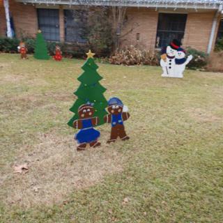 A cheerful Christmas scene featuring a decorated tree and festive figures in a front yard.
