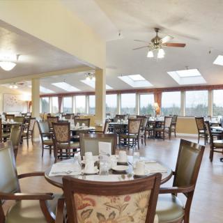 A spacious dining room with elegantly set tables and large windows allowing natural light.