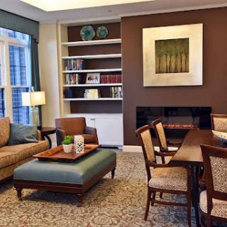 A cozy living room featuring modern furniture, a wooden dining table, and decorative shelves.