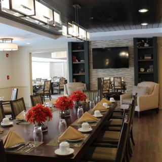 A well-decorated dining room with a large table, elegant lighting, and floral centerpieces.