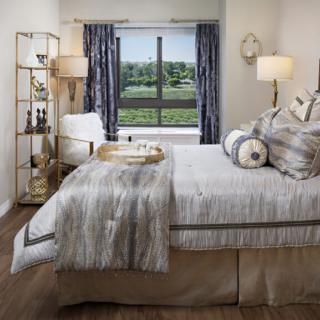 A modern and cozy bedroom with neutral colors, featuring a neatly made bed, stylish decor, and a scenic window view.