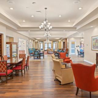 A spacious and elegantly designed lounge area featuring comfortable seating, modern chandeliers, and wooden flooring.