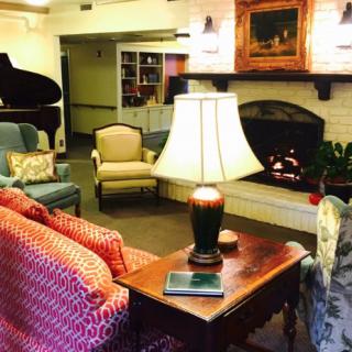 Cozy living room with comfortable seating, a grand piano, and a warm fireplace.