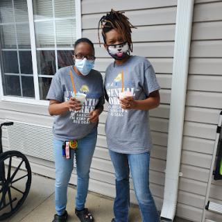 Two individuals enjoying a moment outdoors while wearing masks and casual attire.