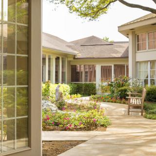 A serene garden courtyard with pathways and benches under a sunny sky.