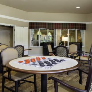 A cozy recreation room featuring a checkers game table surrounded by comfortable chairs.