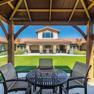 A view from the gazebo overlooks a spacious backyard leading to a modern house.