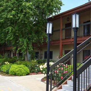 A two-story building with outdoor stairs, surrounded by lush greenery and landscaped gardens.