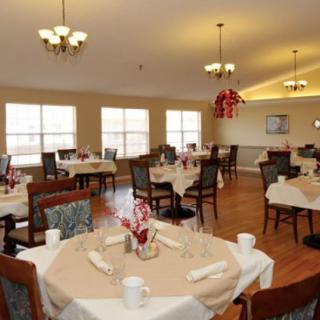 A well-lit dining room with elegantly set tables and chairs.