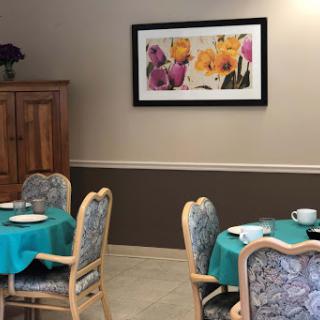 A cozy dining area featuring teal tables and floral artwork on the wall.