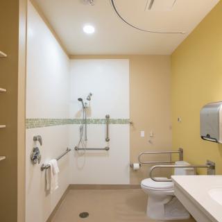 A modern and accessible bathroom equipped with a shower, toilet, sink, and grab bars.