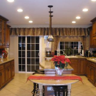 A modern kitchen interior featuring wooden cabinets, an island with a poinsettia centerpiece, and bright overhead lighting.