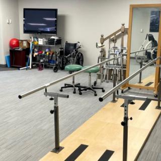 A physical therapy room equipped with parallel bars and various rehabilitation tools.
