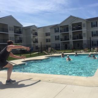People enjoying a sunny day by the swimming pool at an apartment complex.