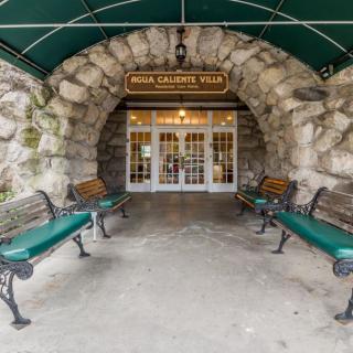 A stone archway entrance with benches and a green awning.