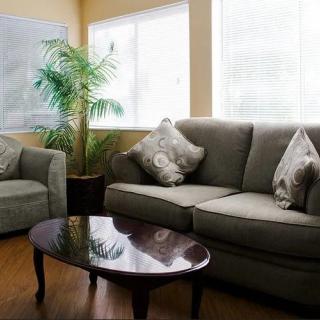 A cozy living room with a sofa, armchair, and coffee table next to a large window.