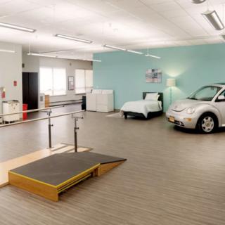 A rehabilitation center's training room equipped with therapy equipment and a car simulation setup.