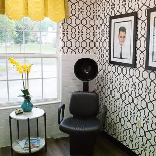 A stylish salon corner with a hair dryer chair, modern wallpaper, and decorative wall art.
