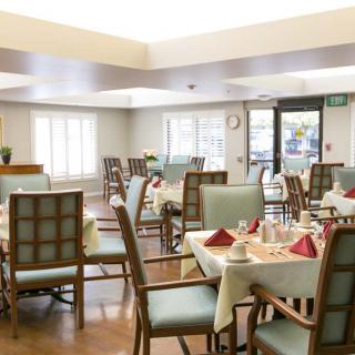 A bright and neatly arranged dining room with multiple set tables and chairs.