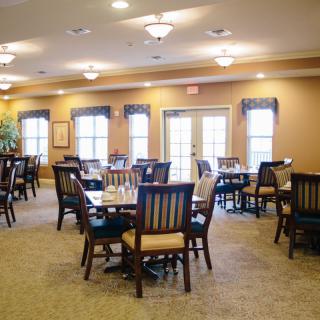 A cozy dining room setup with multiple tables and chairs, featuring warm lighting.