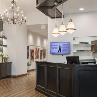 A modern reception area featuring a stylish front desk, elegant chandelier, and contemporary decor.
