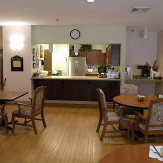 A cozy dining area with wooden tables and chairs, adjacent to a small kitchen space.