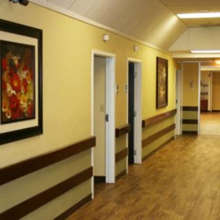 A well-lit hallway with framed artwork on the walls and wooden flooring.
