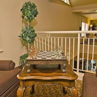 A cozy indoor setting featuring a chess board on a wooden table, complemented by comfortable seating and a decorative plant.