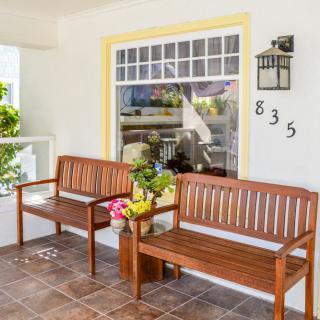 A cozy porch featuring wooden benches and decorative flower pots next to a large window.