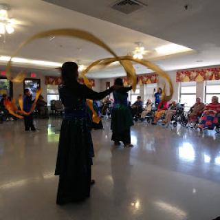 A vibrant dance performance featuring dancers with flowing ribbons in a lively indoor setting.