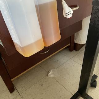 Two liquid containers are placed next to a wooden cabinet in a kitchen setting.