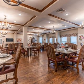 A spacious and elegantly designed dining room with wooden flooring and comfortable seating.